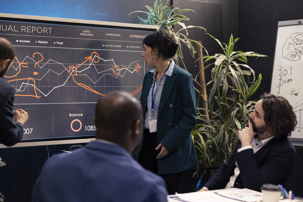 Executive team reviewing performance data and business metrics on a digital dashboard in a boardroom setting